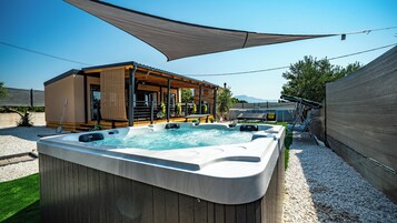Ein Whirlpool mit einer Holzterrasse und einem überdachten Sitzbereich.