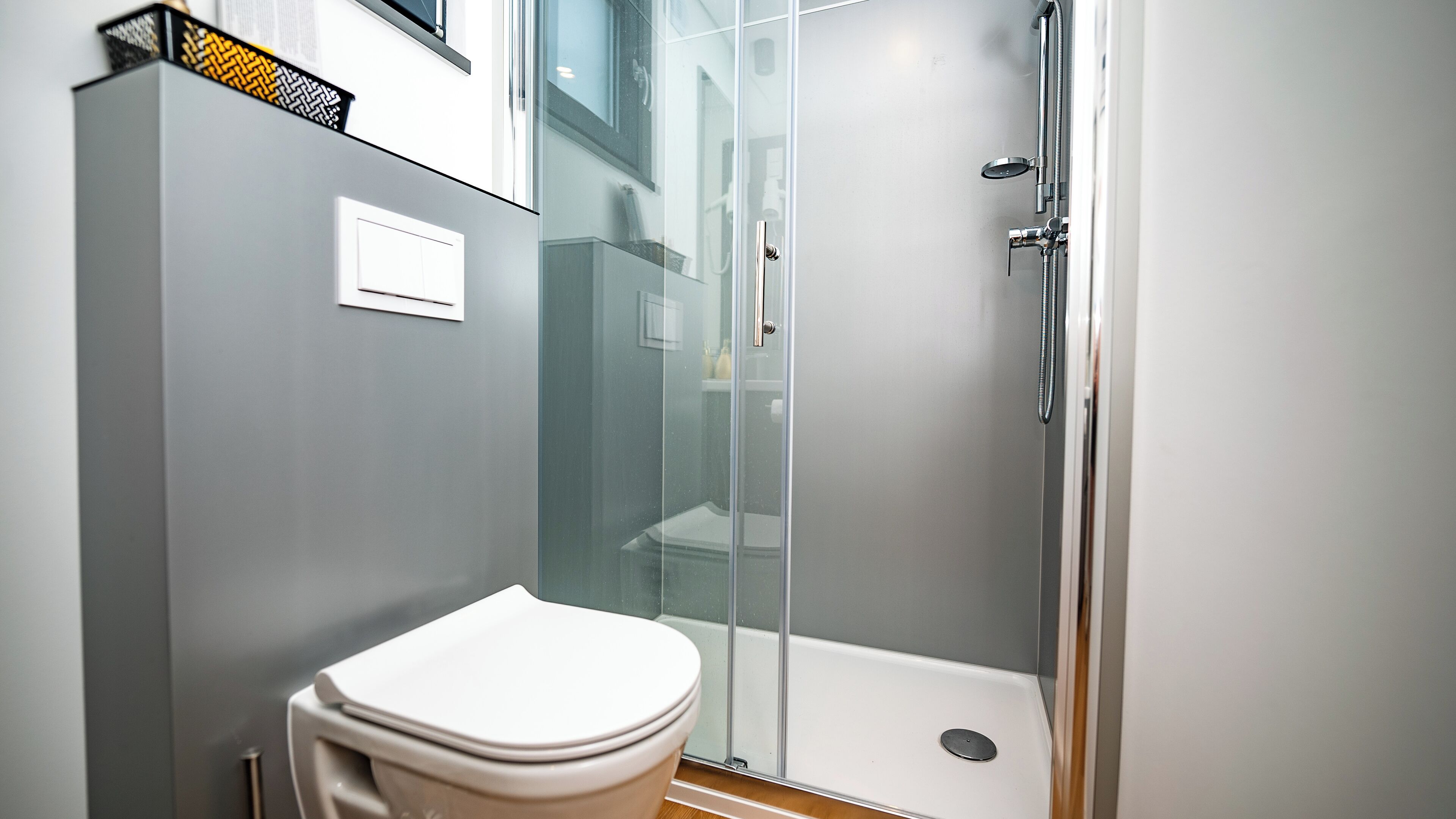 Een moderne badkamer met toilet, een douchecabine van glas en een zichtbare toiletrolhouder.