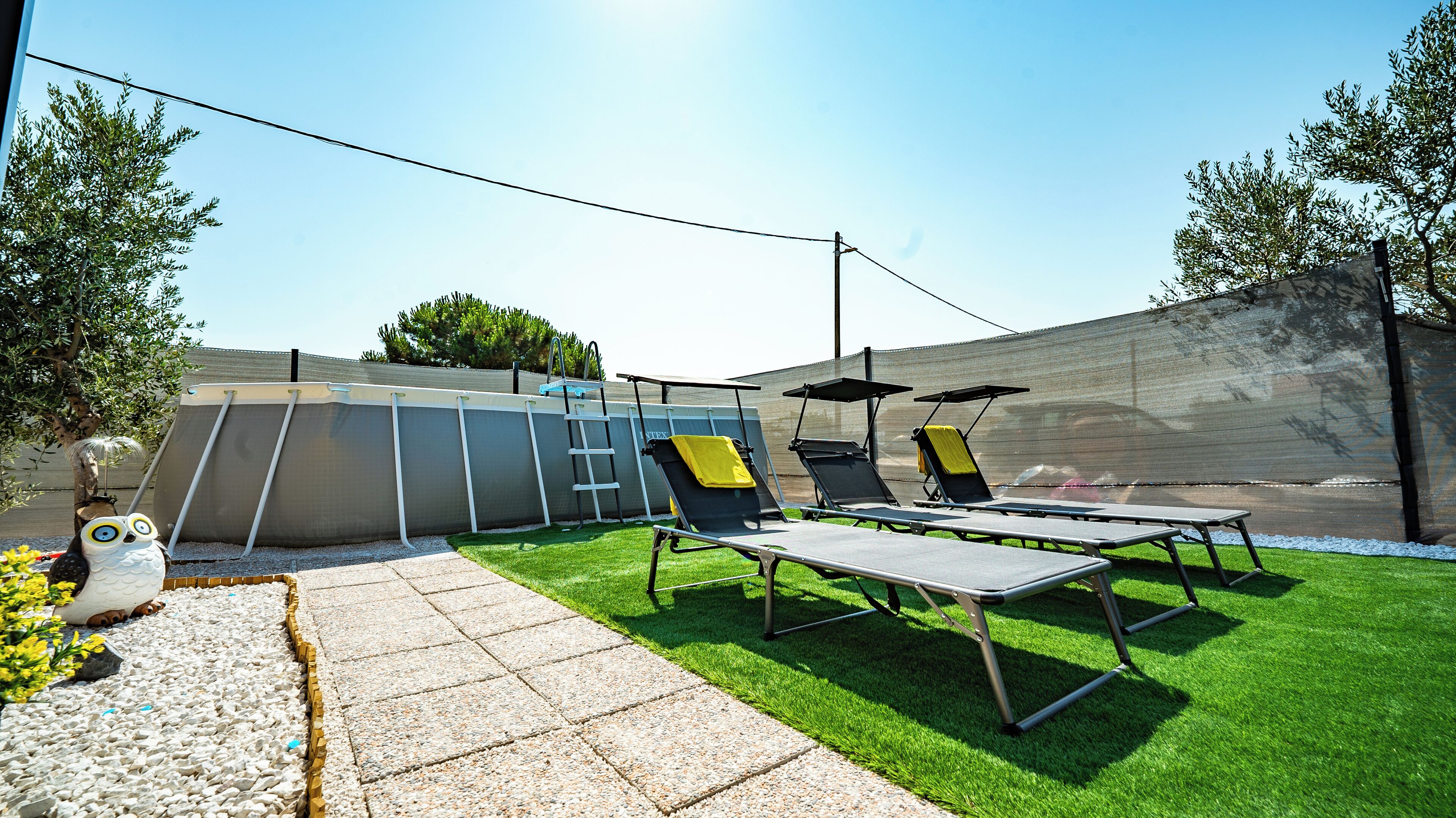 An outdoor pool area with lounge chairs and a ladder.