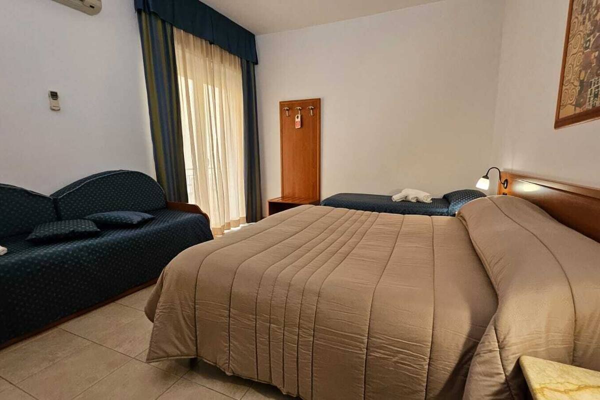 A hotel room with a bed, a sofa, a desk, and a wardrobe.