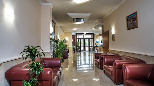 Un vestíbulo de hotel con asientos de cuero, plantas en macetas y una zona de recepción.
