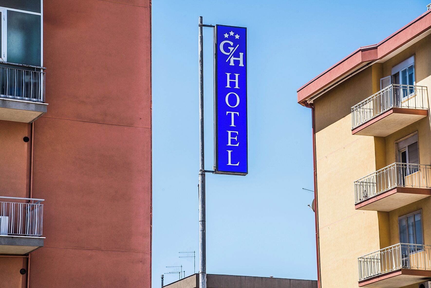 Segnaletica di un hotel con la scritta "GH HOTEL" e stelle sopra le lettere.