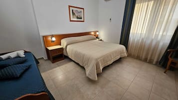 Habitación de hotel con una cama, una cama individual, una mesita de noche, una lámpara y un cuadro en la pared.