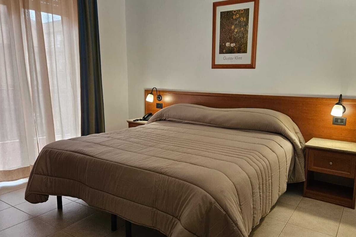 A neatly made bed with a headboard, bedside tables with lamps, and a framed picture on the wall.