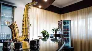 Una zona de bar con un gran saxofón dorado, vasos negros y una barra moderna.