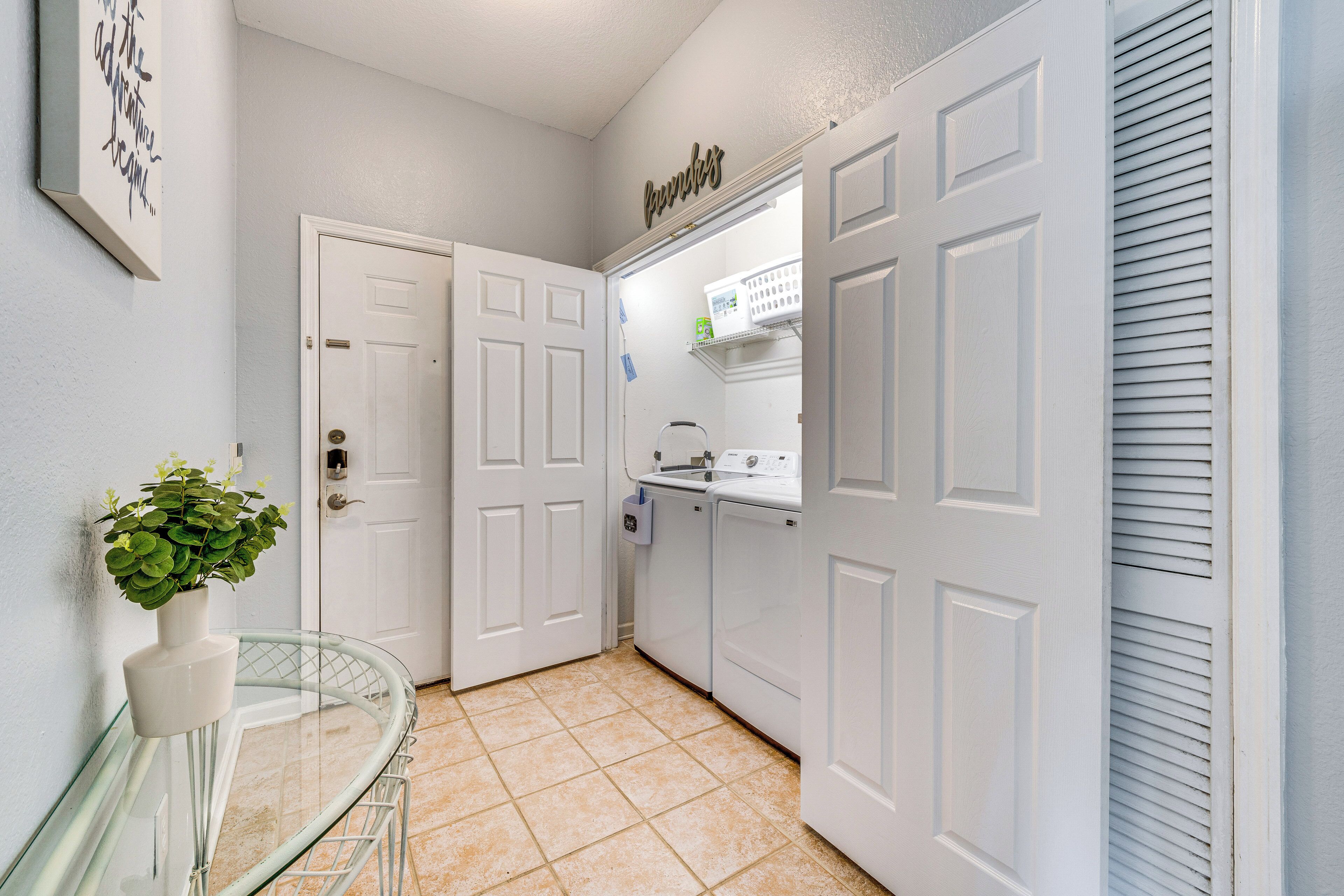 A laundry room with a washing machine, dryer, and a shelf with laundry supplies.