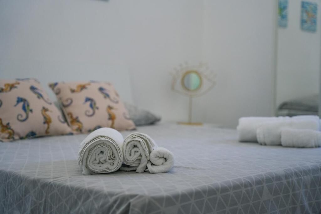 A neatly made bed with rolled towels and patterned pillows.