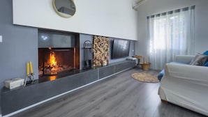 Un salon moderne avec une cheminée, un téléviseur à écran plat fixé au-dessus, et un canapé confortable.