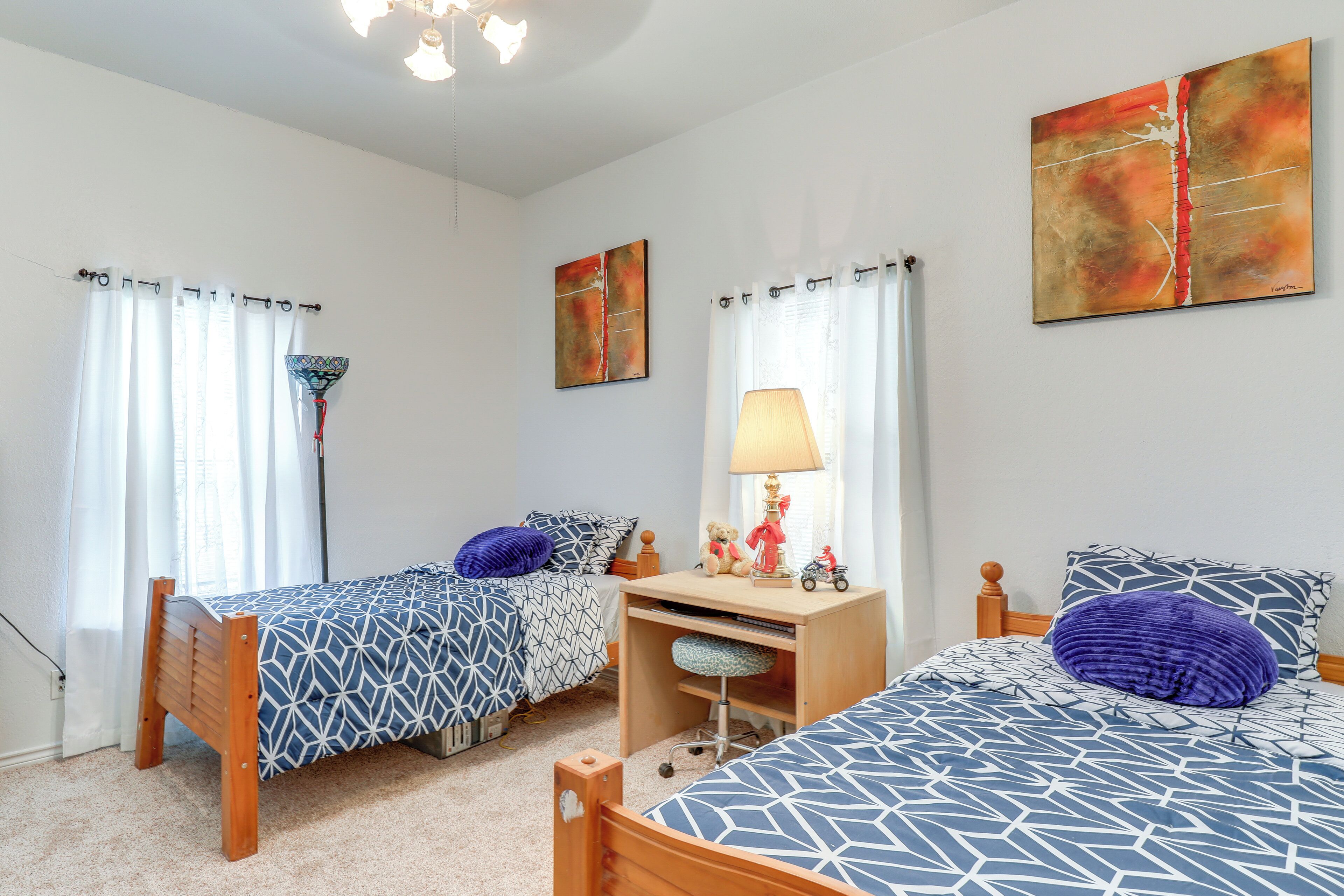 Une chambre avec deux lits simples, un bureau et une chaise.
