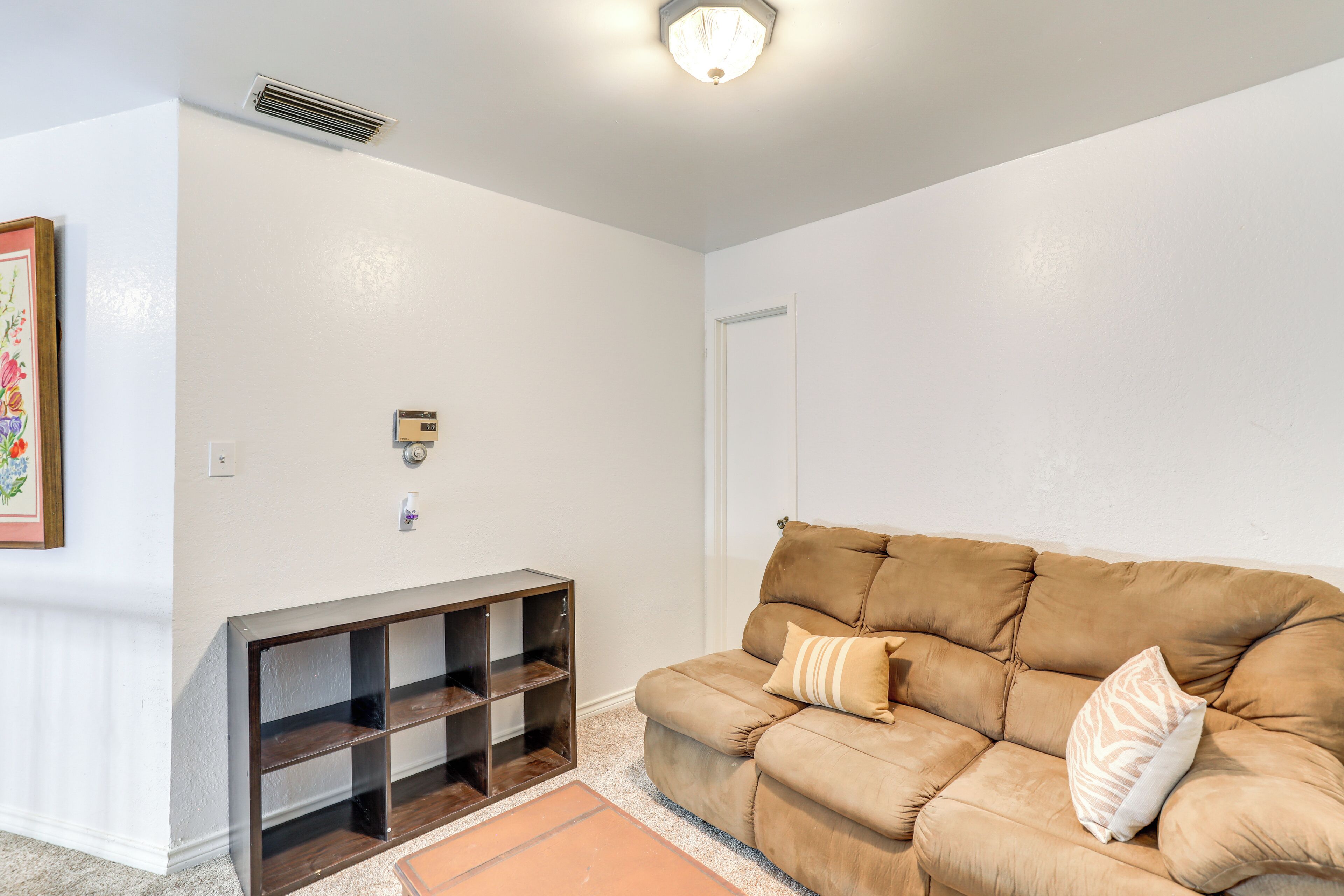 Un soggiorno con un divano color beige, un tavolo consolle in legno e una porta.