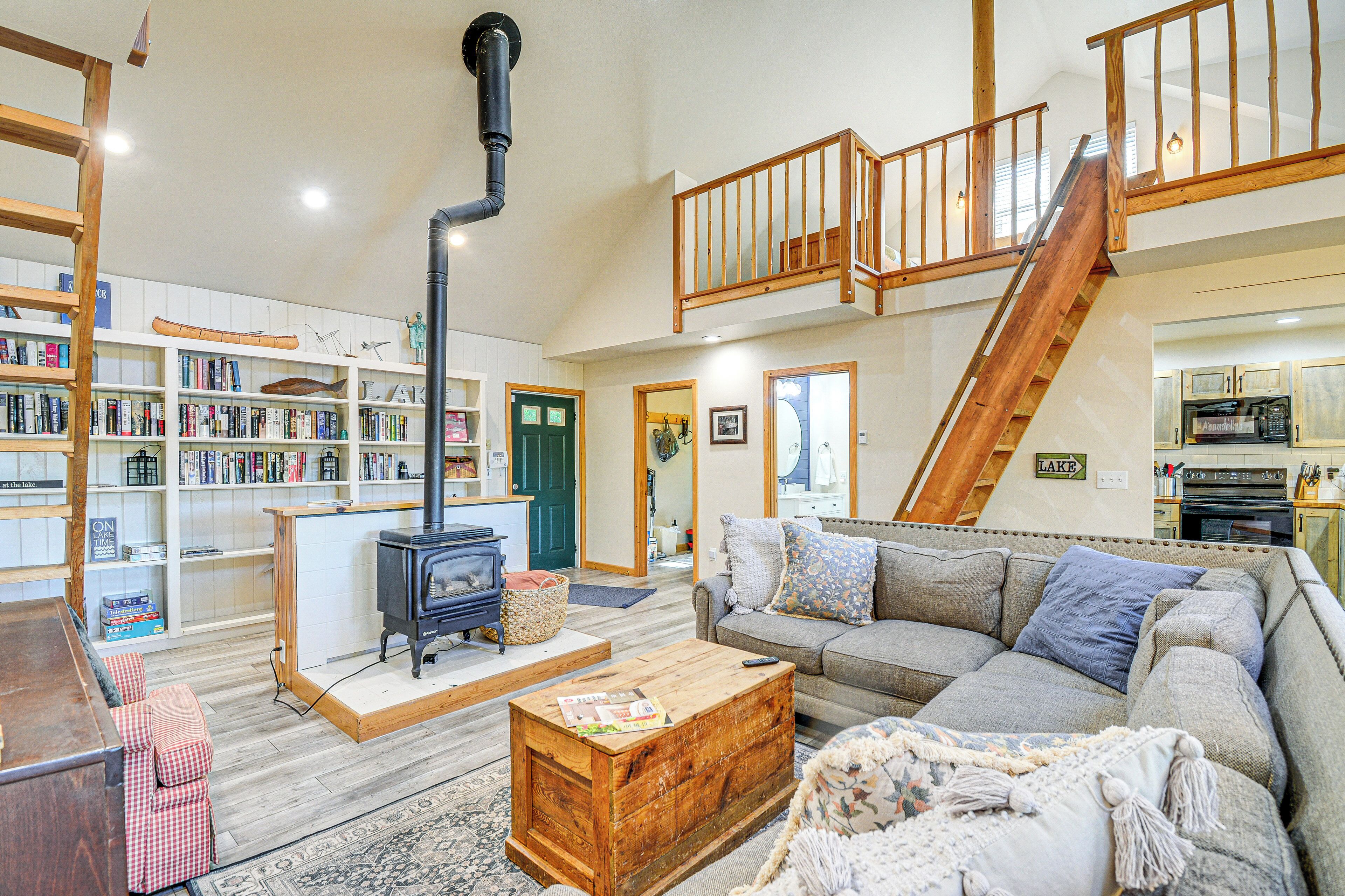 A spacious living room with a fireplace, a staircase, and a kitchen area.