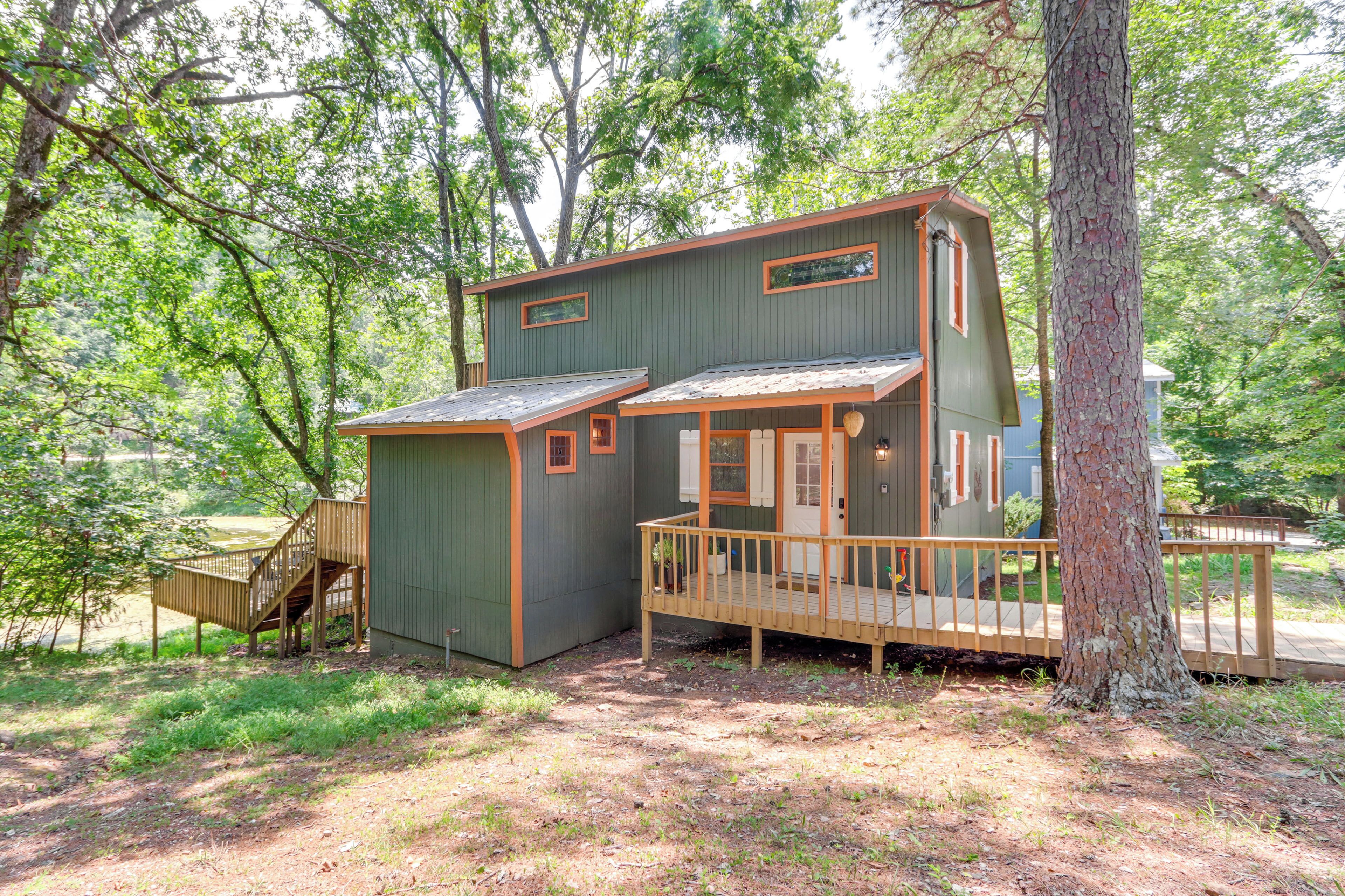 A cabin with a wooden deck, a small porch, and a staircase leading to an upper level.
