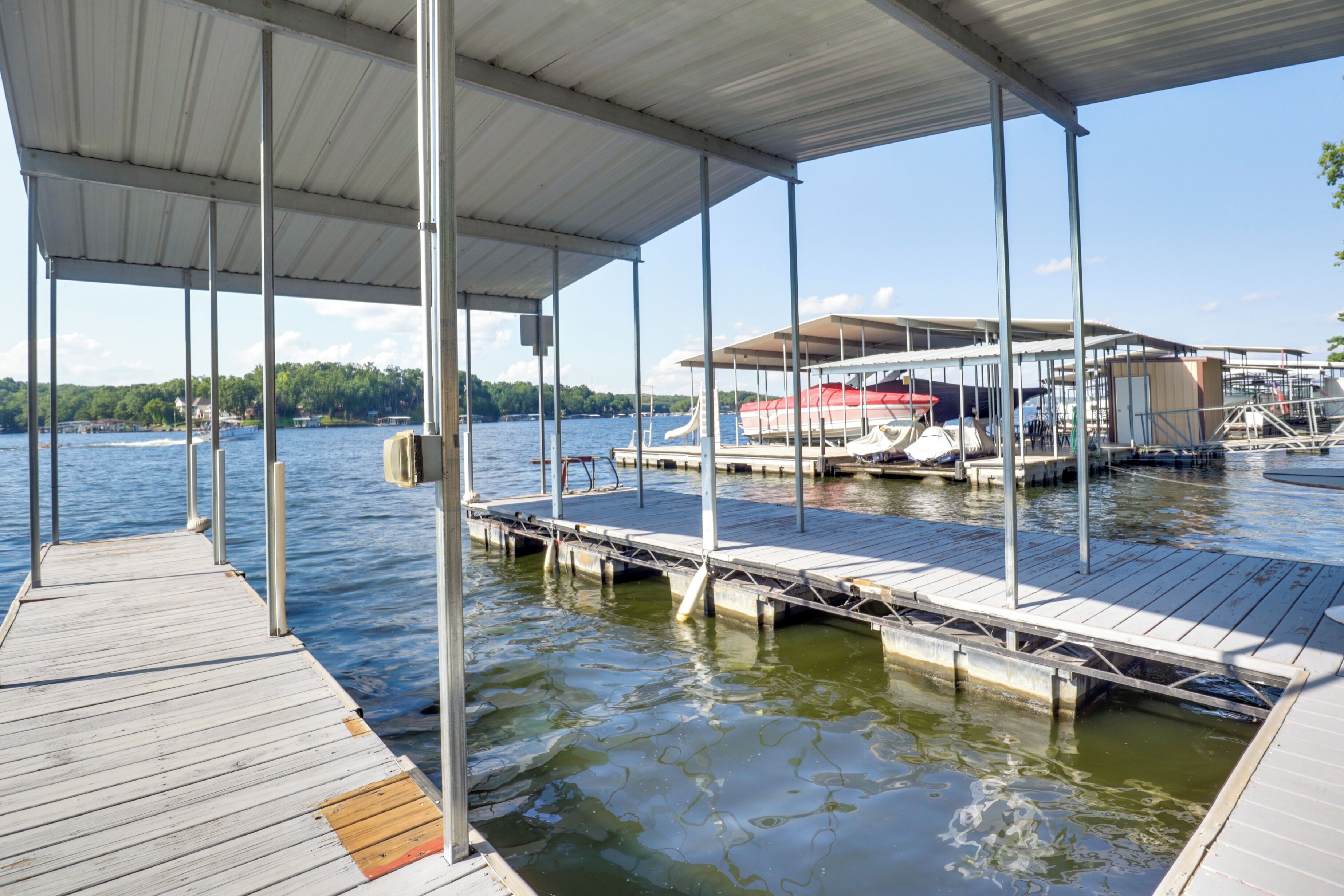 A dock with a covered area, boats, and a lake.