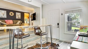 A modern kitchen with a marble countertop, two bar stools, and a cowhide rug.