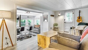 A spacious living room with a wooden coffee table, a sofa, and a guitar on the wall.
