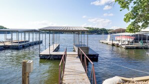A marina with multiple docks and covered areas, calm water, and distant hills.