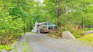 Une cabane dotée d’un porche, entourée d’une forêt dense.