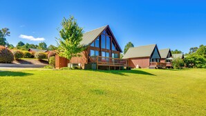 A large, modern building with a prominent glass facade and a balcony, surrounded by a well-maintained lawn and trees. - Lake Keowee Retreat: Idyllic Six Mile Cabin! (Six Mile)