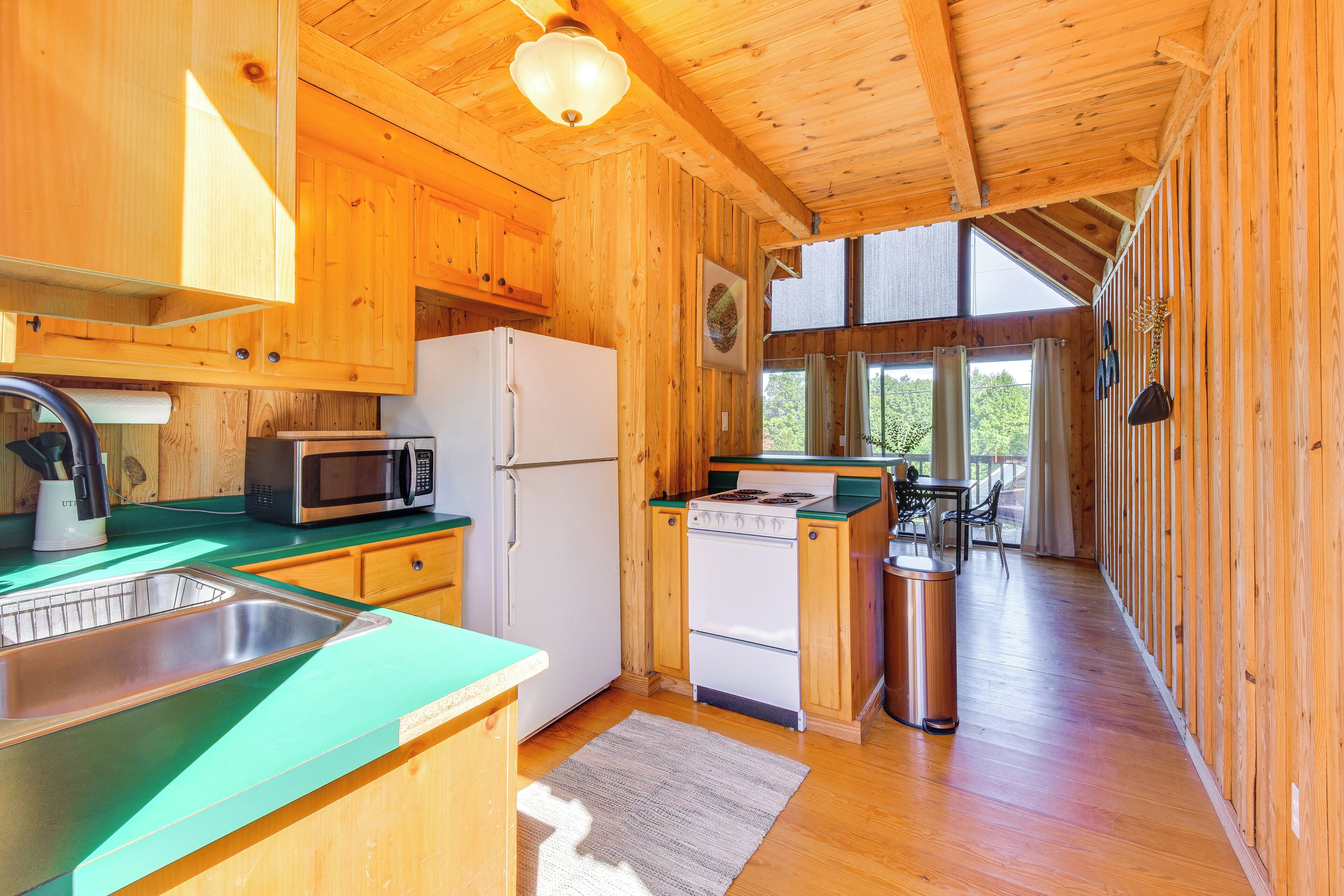 Cocina de cabaña de madera con refrigerador, microondas, estufa y pileta.