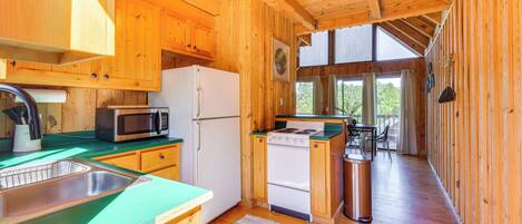 Cocina de cabaña de madera con refrigerador, microondas, estufa y pileta.