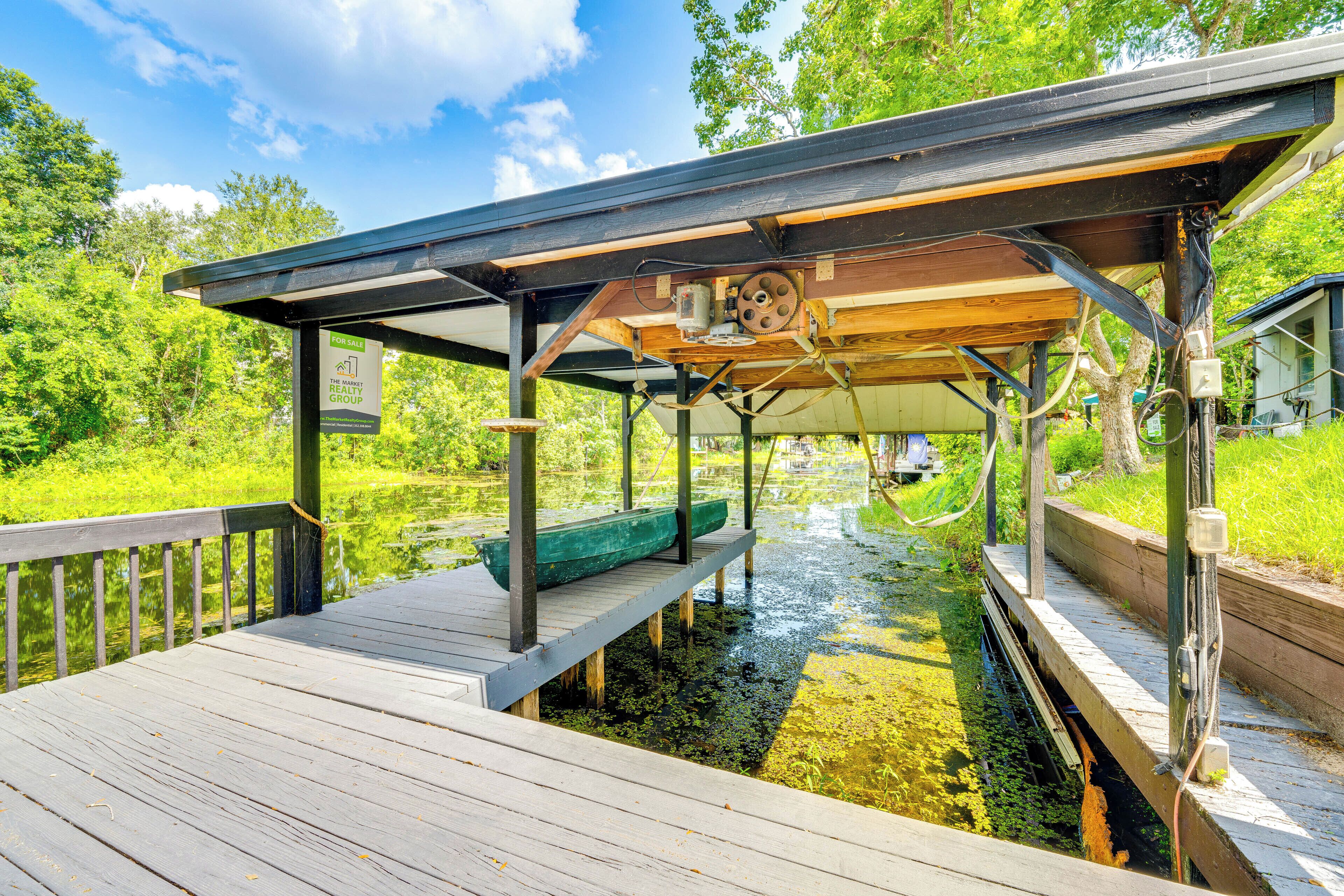 A wooden deck with a covered area, a canoe, and a small stream.