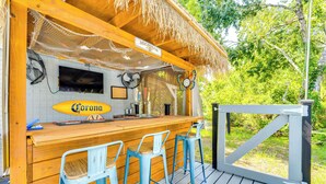 A wooden bar area with a Corona sign, two fans, and a TV screen. - Spacious Tavares Home w/ Private Outdoor Oasis! (Tavares)