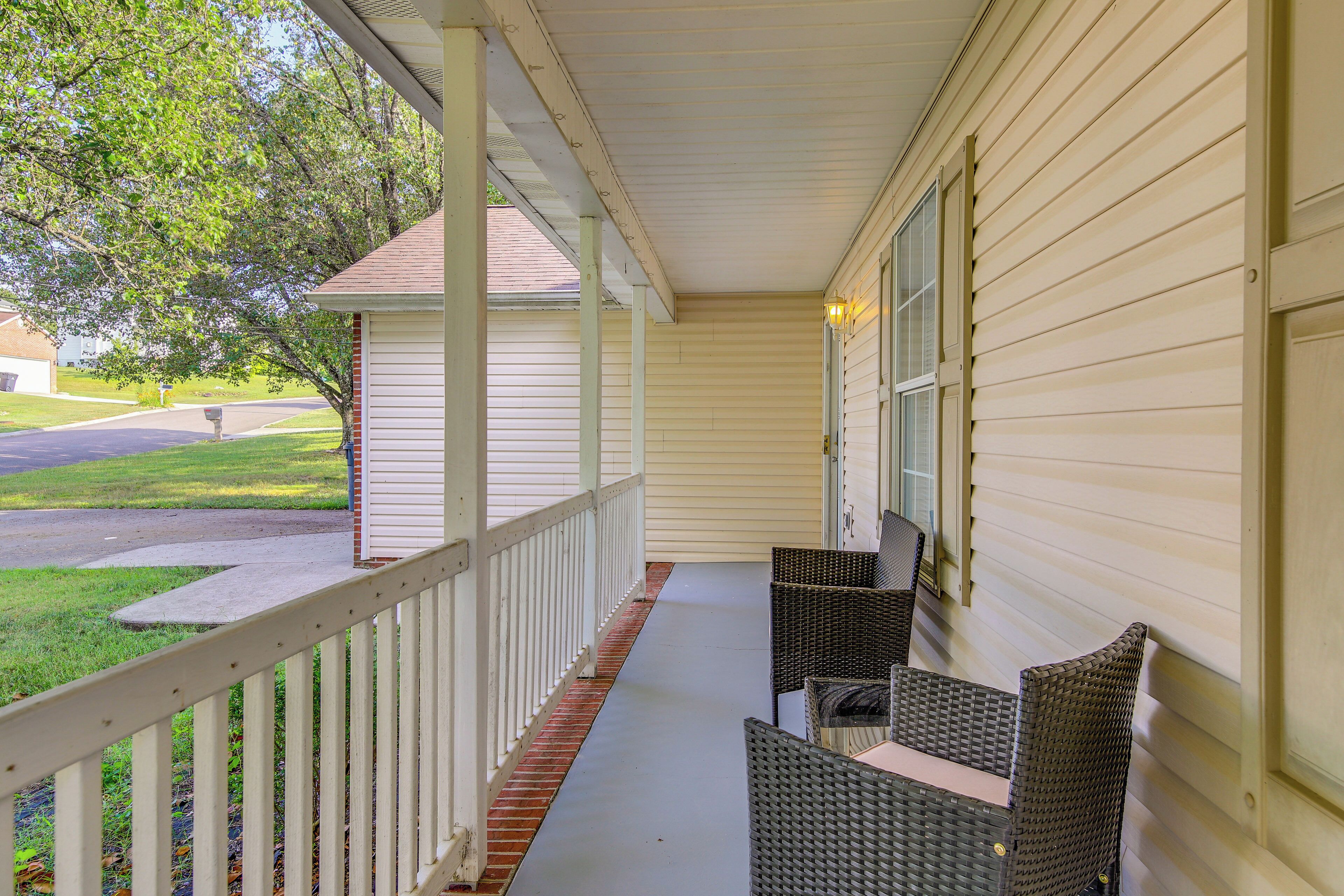 A covered porch with wicker furniture and a white railing.