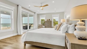 Ein Schlafzimmer mit einem großen Bett, einem Deckenventilator und Blick auf den Strand.