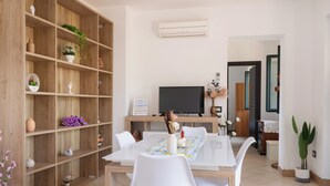 A dining area with a wooden bookshelf, a TV, and a table with chairs.