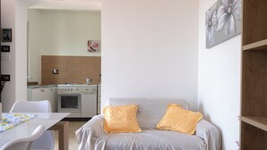 A modern room with a bed, a dining table, and a kitchenette.