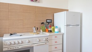 A kitchen with a white stove, white refrigerator, and wooden backsplash.