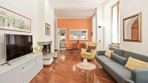 Un salon moderne avec un téléviseur à écran plat, un canapé, un fauteuil et une petite table.