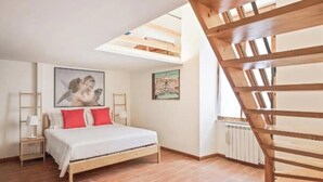 Une chambre avec un lit en bois, une lucarne, un radiateur et un escalier.
