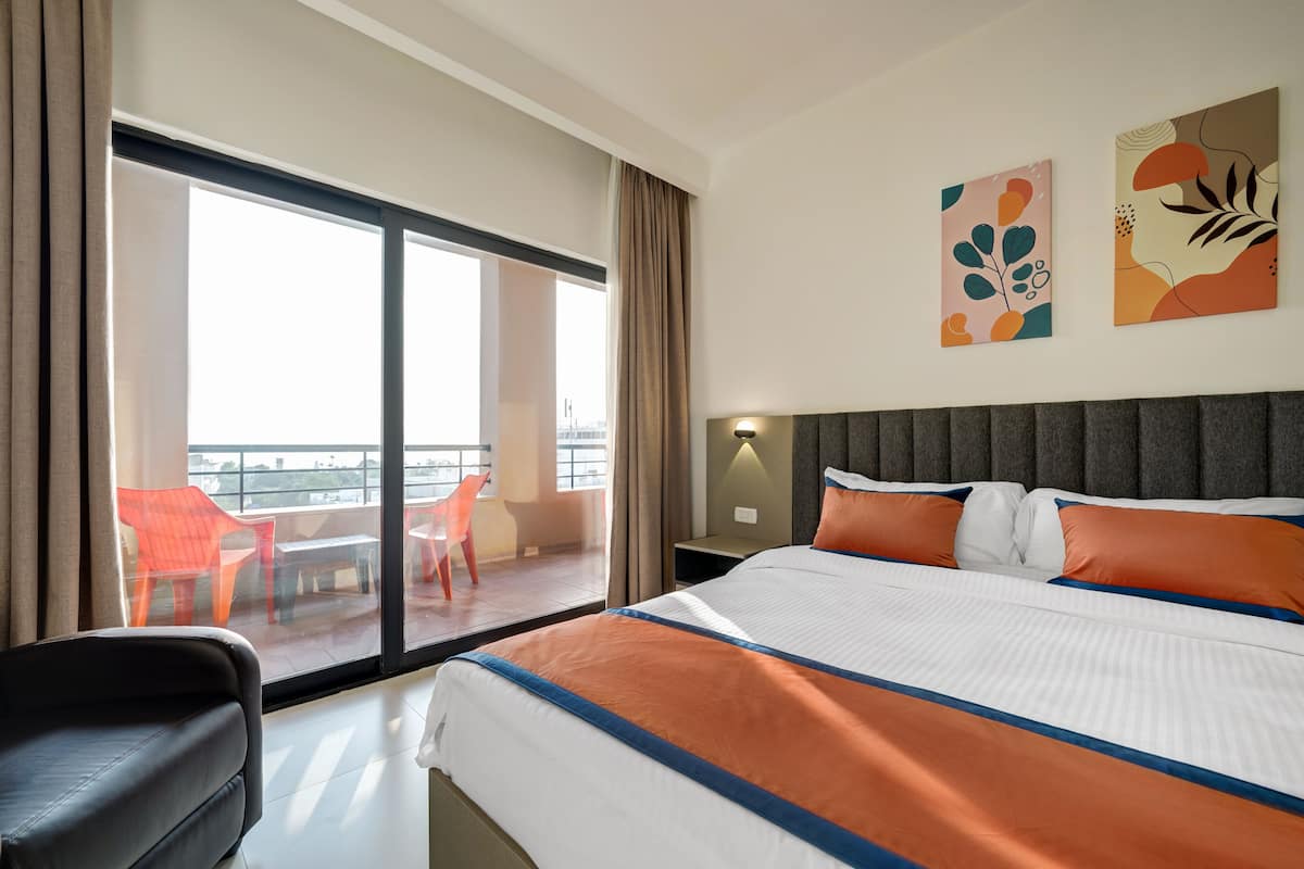 Ein Hotelzimmer mit einem großen Bett, Blick auf den Balkon und zwei an der Wand befestigte Kunstwerke.