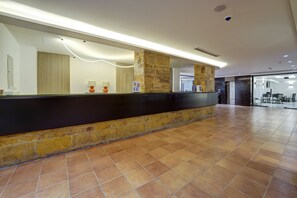 A reception area with a black counter, stone pillars, and a tiled floor. - The Loft By FHM (Aqaba)