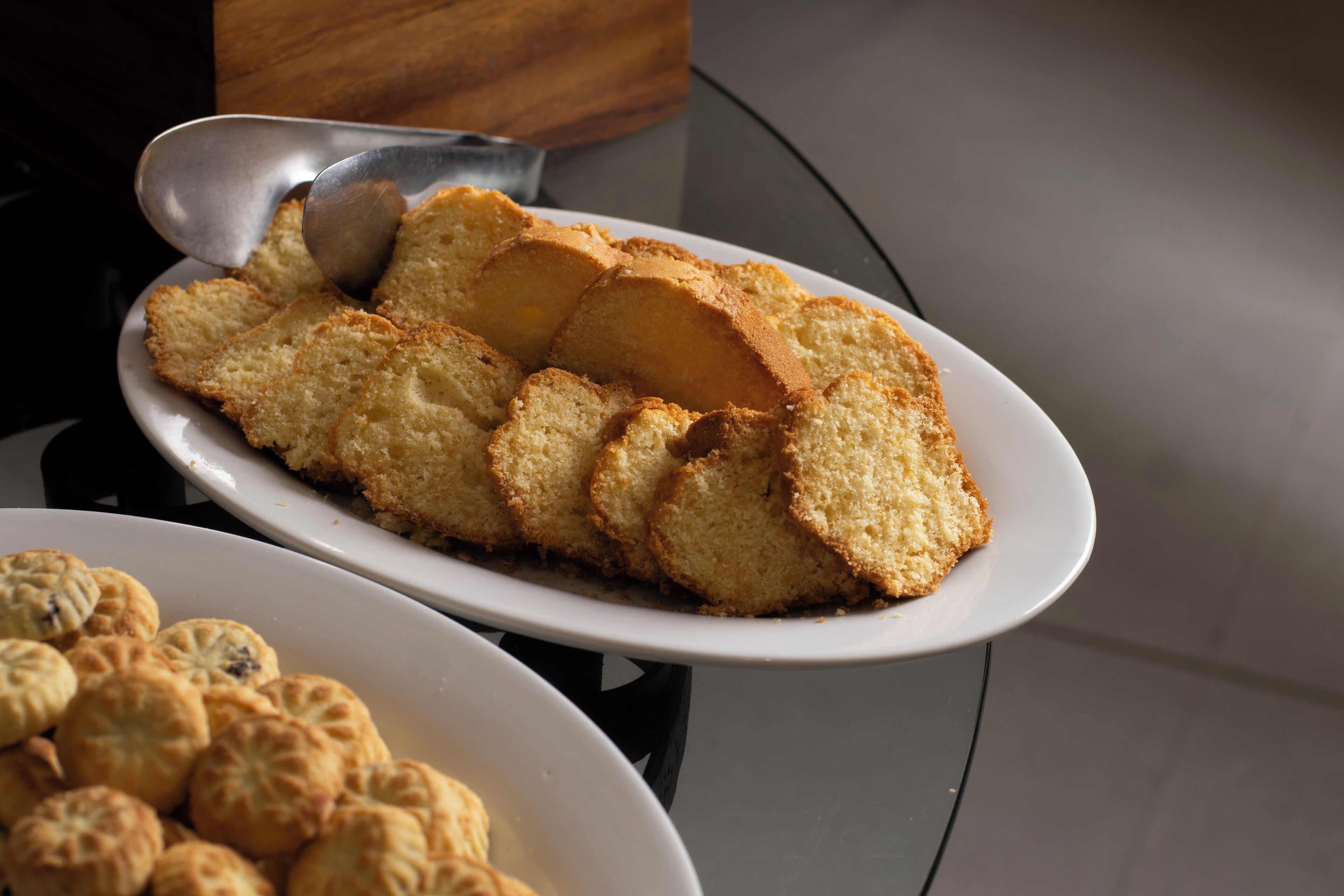 A plate of sliced sponge cake and a plate of round pastries.
