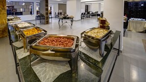Zona de buffet con diversas opciones de comida, incluyendo perritos calientes y otros platos, en un hotel moderno.