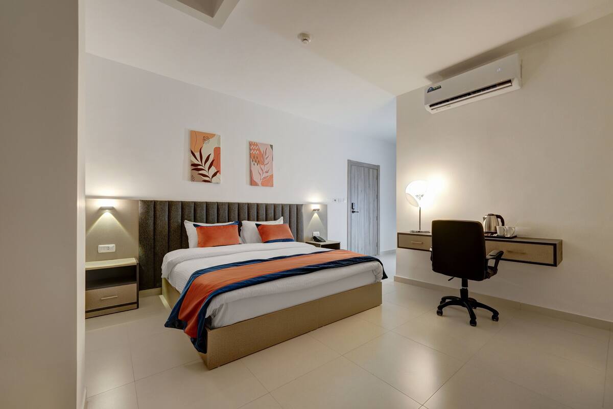 Ein modernes Schlafzimmer mit Bett, Nachttischen, einem Schreibtisch und einer Klimaanlage.