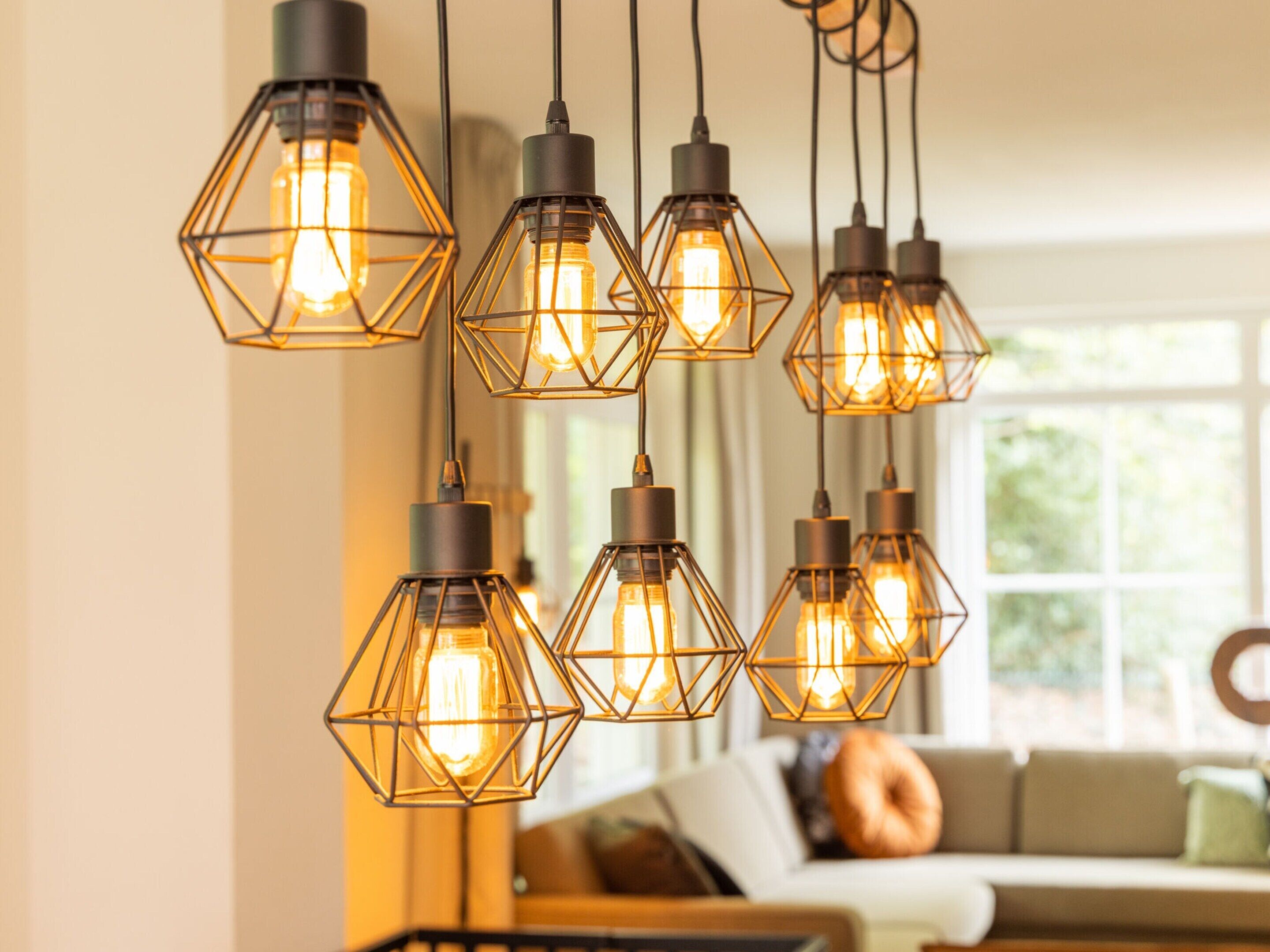 A modern living room with a geometric pendant light fixture and a large window.