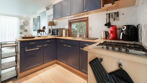 A modern kitchen with dark blue cabinets, a wooden countertop, a gas stove, and various appliances. - Holiday Home in Garderen by Veluwe (Garderen)