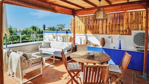 A covered outdoor seating area with a wooden table and chairs, a sofa, and a hanging light fixture. - Casa Vivienne: Puerto de Mogan Beach, Gran Canaria (Peurto De Mogan)