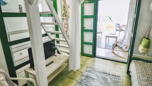 A room with a staircase, a desk with a computer, a chair, and a view of an outdoor area with a table and chairs. - Casa Vivienne: Puerto de Mogan Beach, Gran Canaria (Peurto De Mogan)
