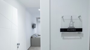 A modern hotel corridor with a clear sign reading "DUOMO" and a minimalist statue decoration. - CATANIA E DINTORNI LIVING ROOMS (Catania)
