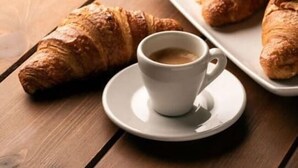 A croissant and a cup of coffee on a wooden table. - CATANIA E DINTORNI LIVING ROOMS (Catania)