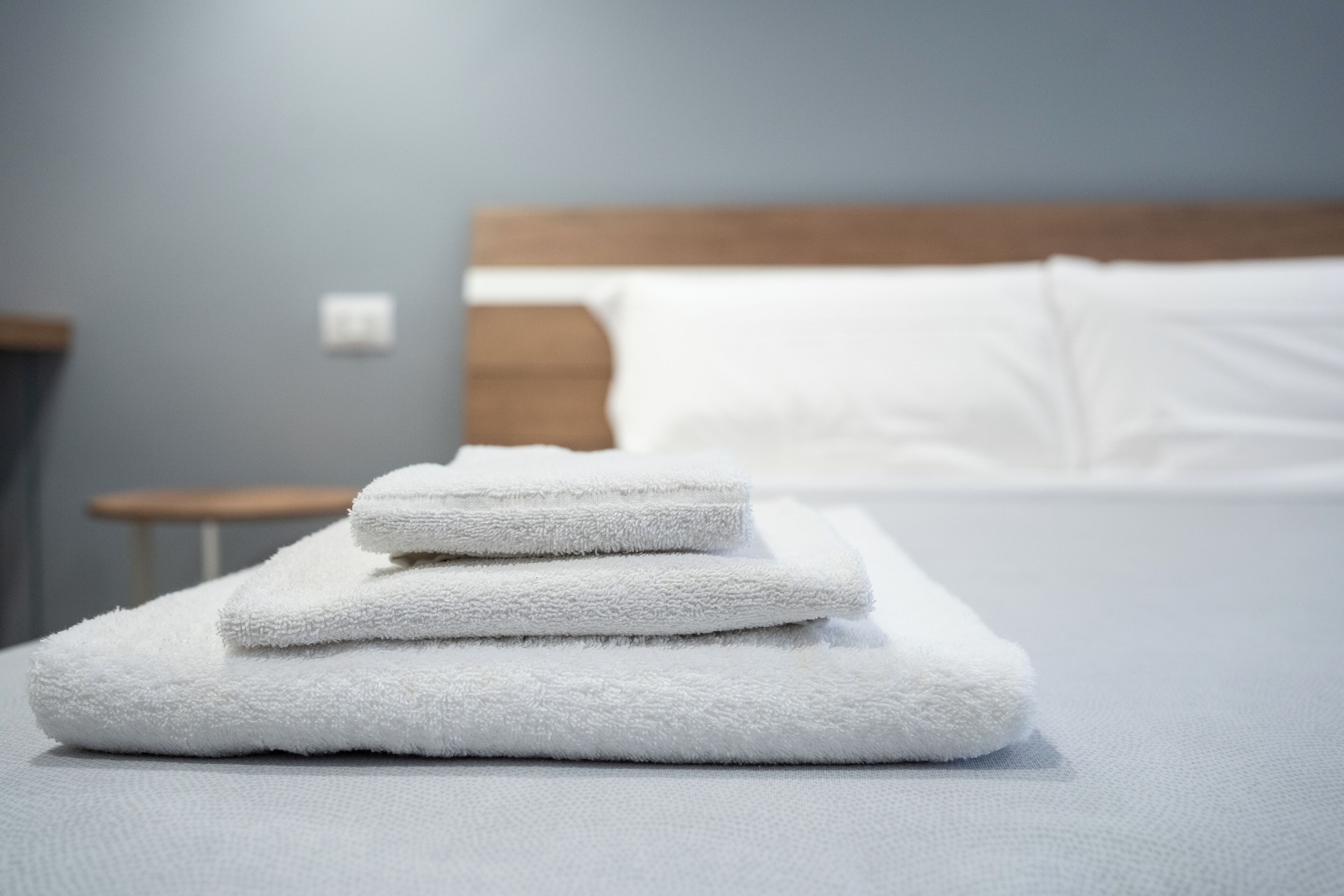Un montón ordenado de toallas blancas sobre una cama en una habitación de hotel.