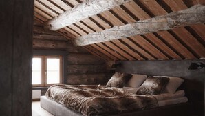 Un dormitorio tipo cabaña de madera con una cama, una ventana y techo de madera.