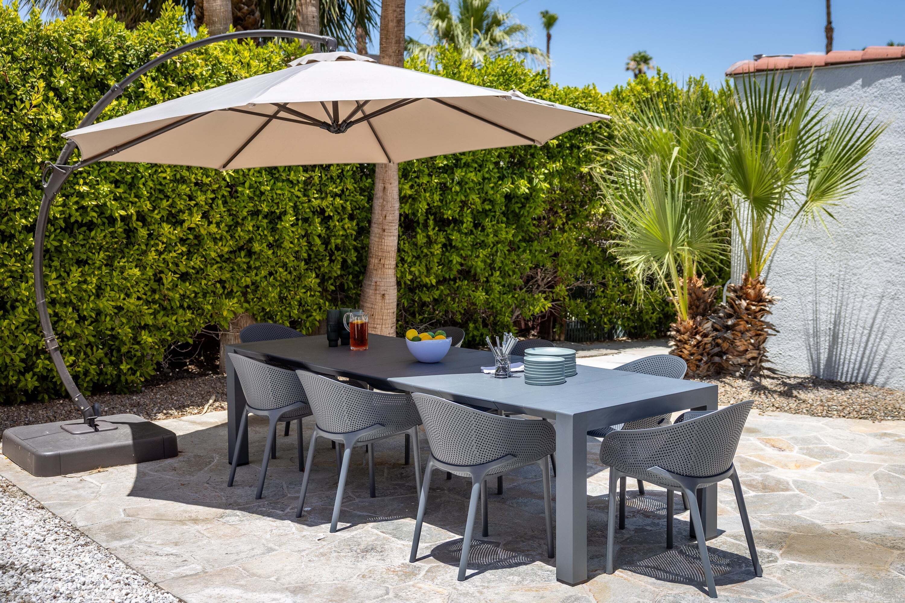 An outdoor patio with a table, chairs, an umbrella, and a stone floor.