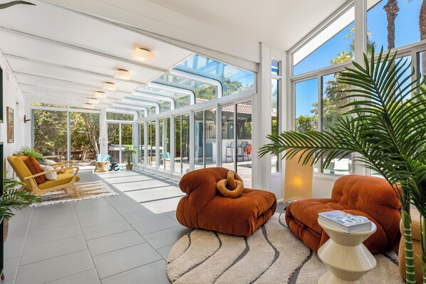A spacious indoor area with large windows, a yellow armchair, and two brown bean bag chairs.