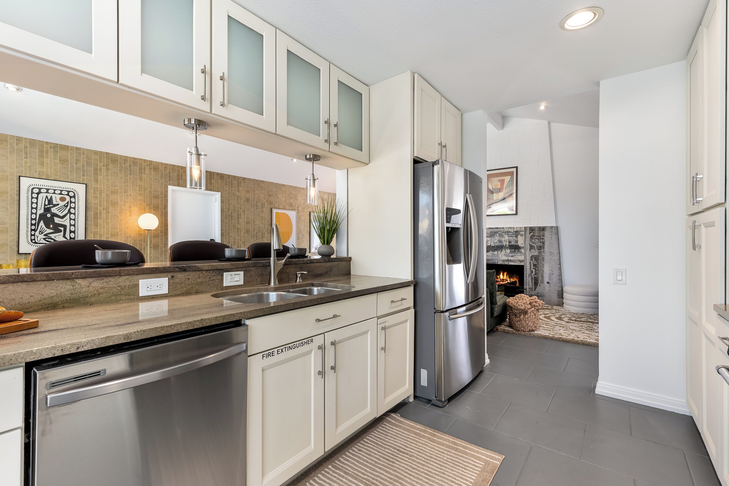 A modern kitchen with stainless steel appliances, white cabinetry, and a built-in dishwasher.