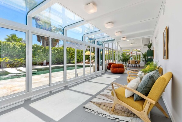 A spacious indoor area with large windows, a pool, and comfortable seating.